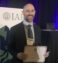 Man smiling, holding award in both hands